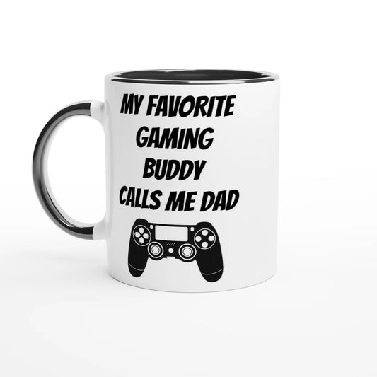 Vit mugg med svart handtag och svart insida med texten My favorite gaming buddy calls me dad och en spelhandkontroll