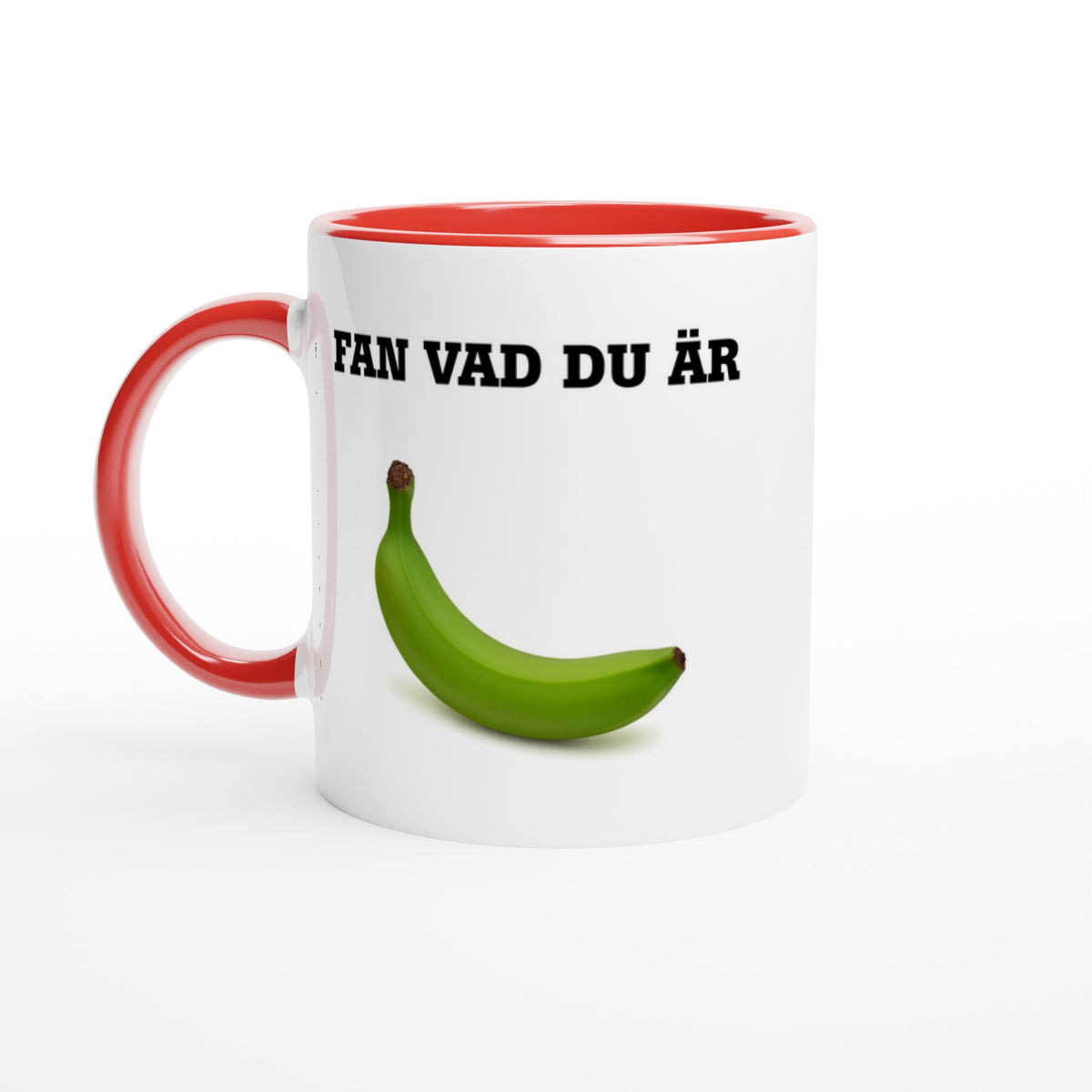 Vit mugg med rött handtag och röd insida med texten Fan vad du är och en grön omogen banan