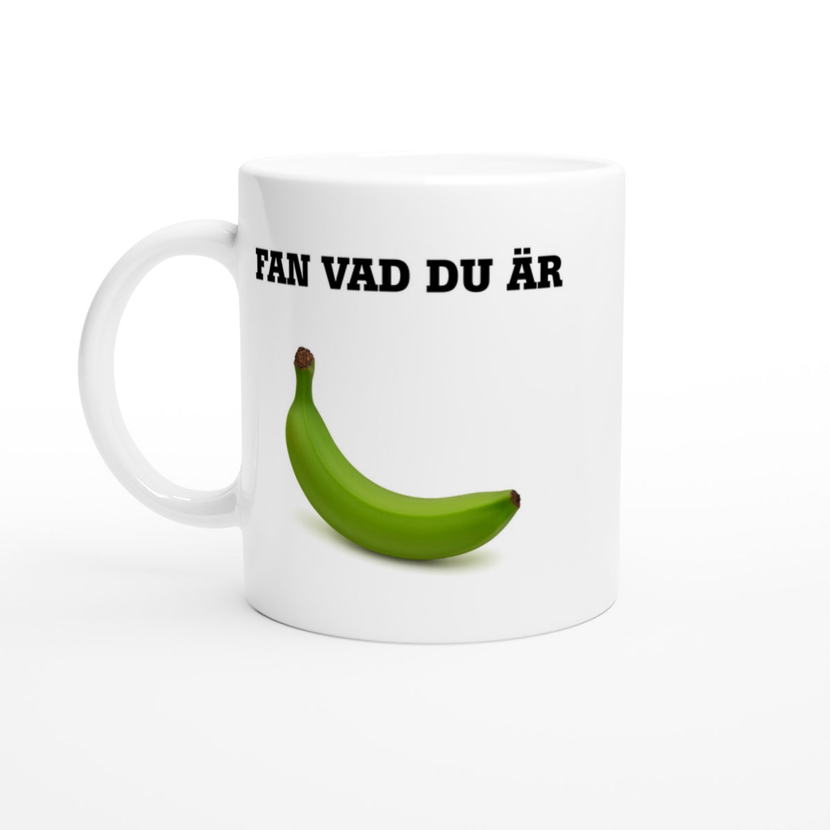 Helvit mugg med texten Fan vad du är och en grön omogen banan